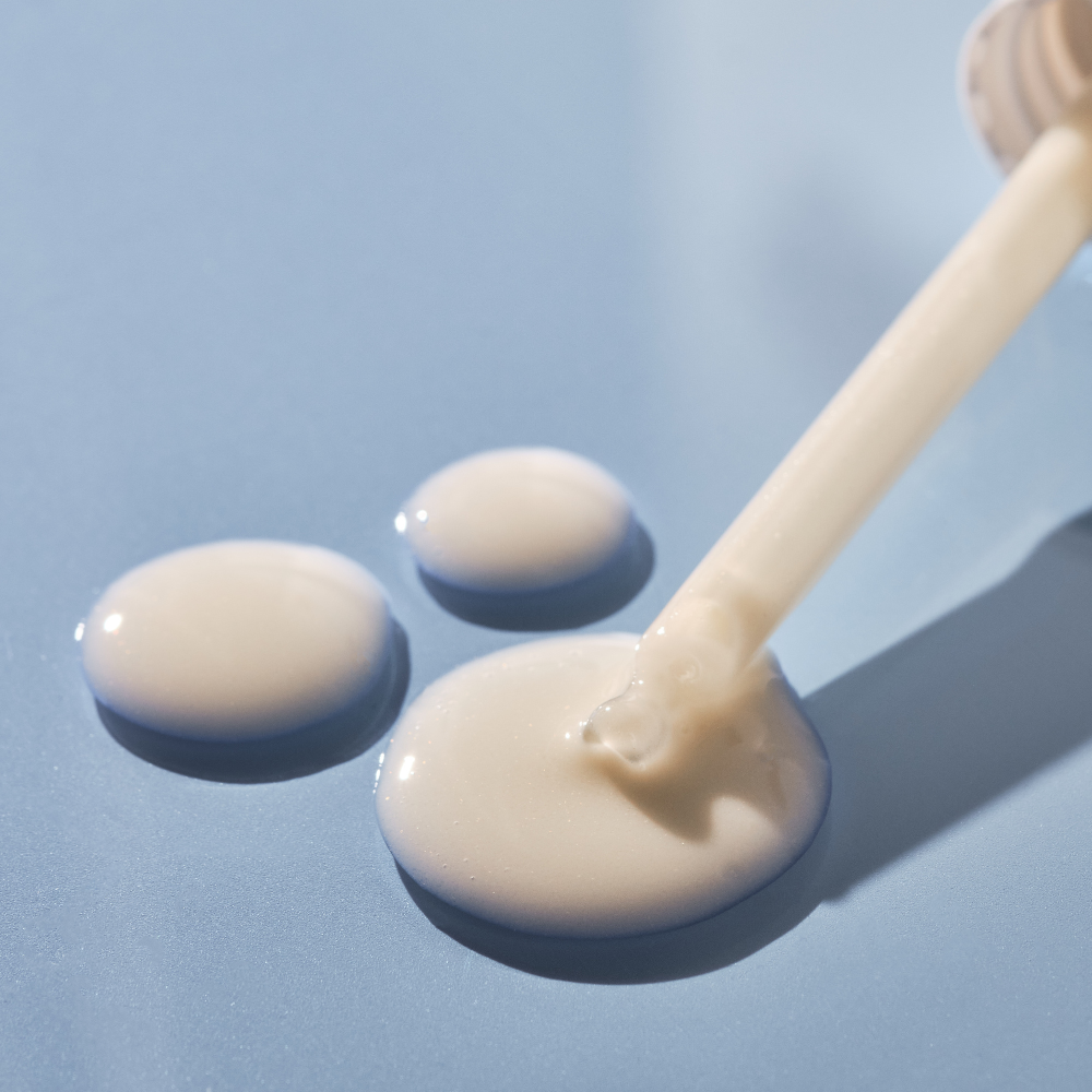 Dipstick with cream-colored substance on a light blue background