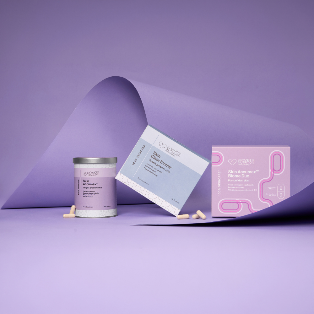 A skincare product set on a lavender studio background, featuring a white jar labeled Skin Moisture with a silver lid, a light blue box labeled Skin Barrier, and a pink box labeled Skin Acne Mask, with a few beige capsules scattered nearby.