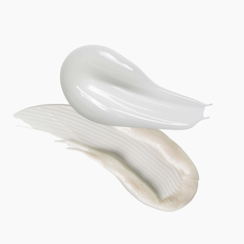 A thick, glossy white cream or lotion swatch shown in two textured smears against a clean white background.