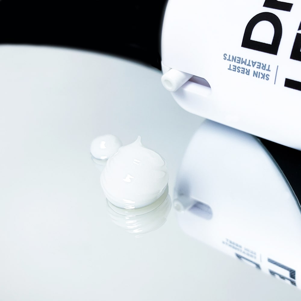 Close-up of skincare products with a focus on a bottle cap and container.