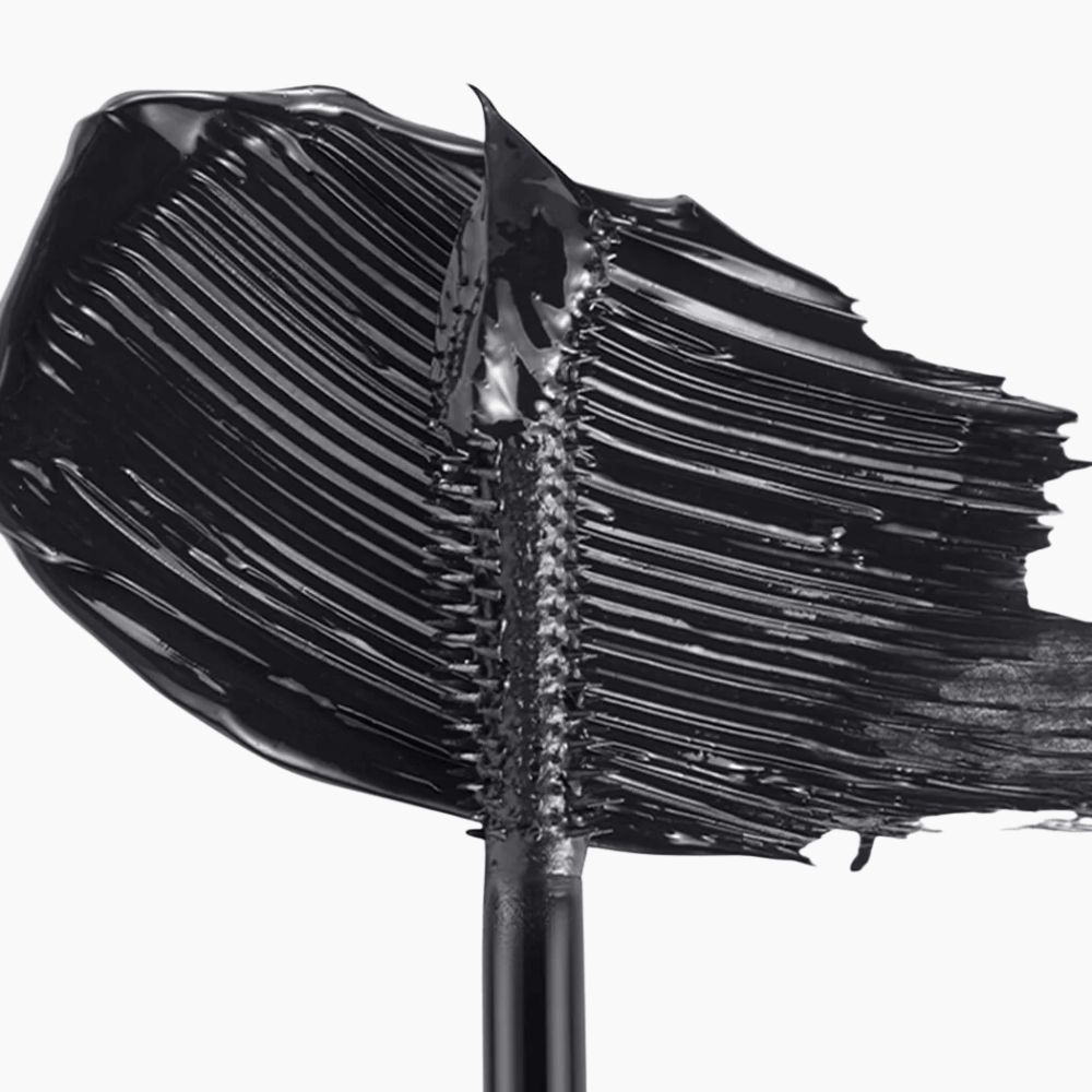 A close-up of a black cosmetic cream or gel swatch applied to a brush, showing the thick, glossy texture of the product against a clean white background.